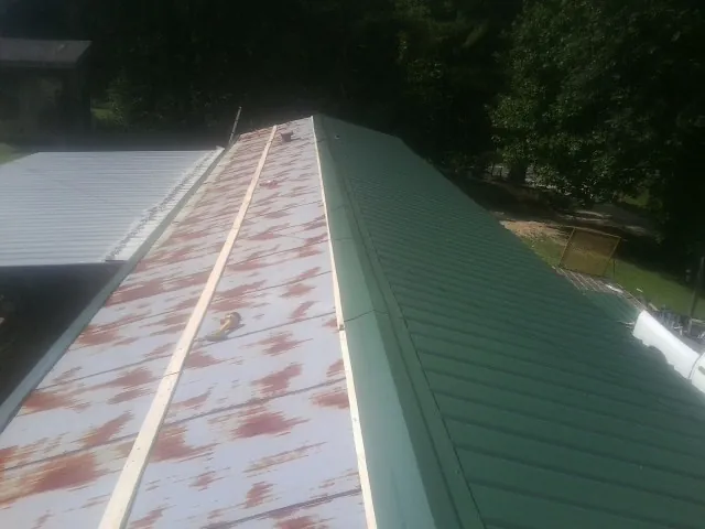 Old rusted panels beside newly installed green metal roofing — Wind Damage Roof Repair by Roofing Brothers in Hillsborough