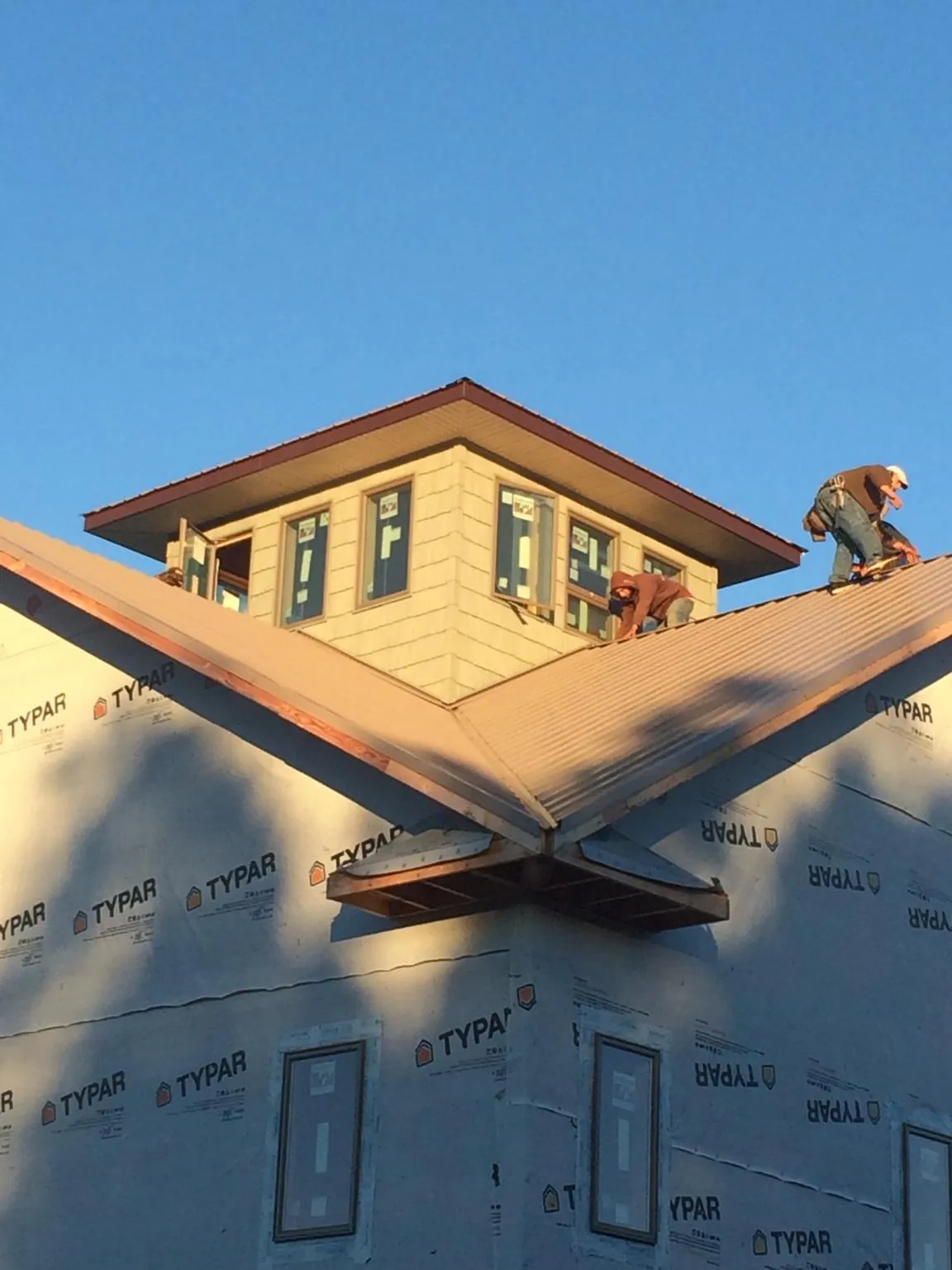 Roofers working around a rooftop cupola on a new metal roof at sunset — Roof Waterproofing in Hillsborough by Roofing Brothers